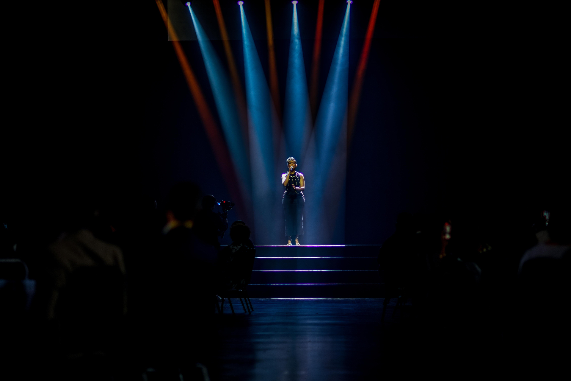 Vocalista em performance solo sob luzes de teatro
